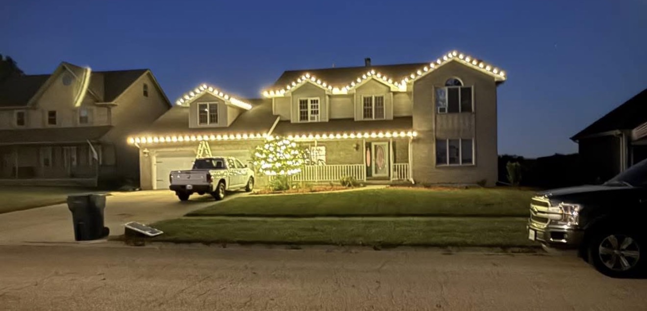 Home with two stories, white roofline lights, and an illuminated tree