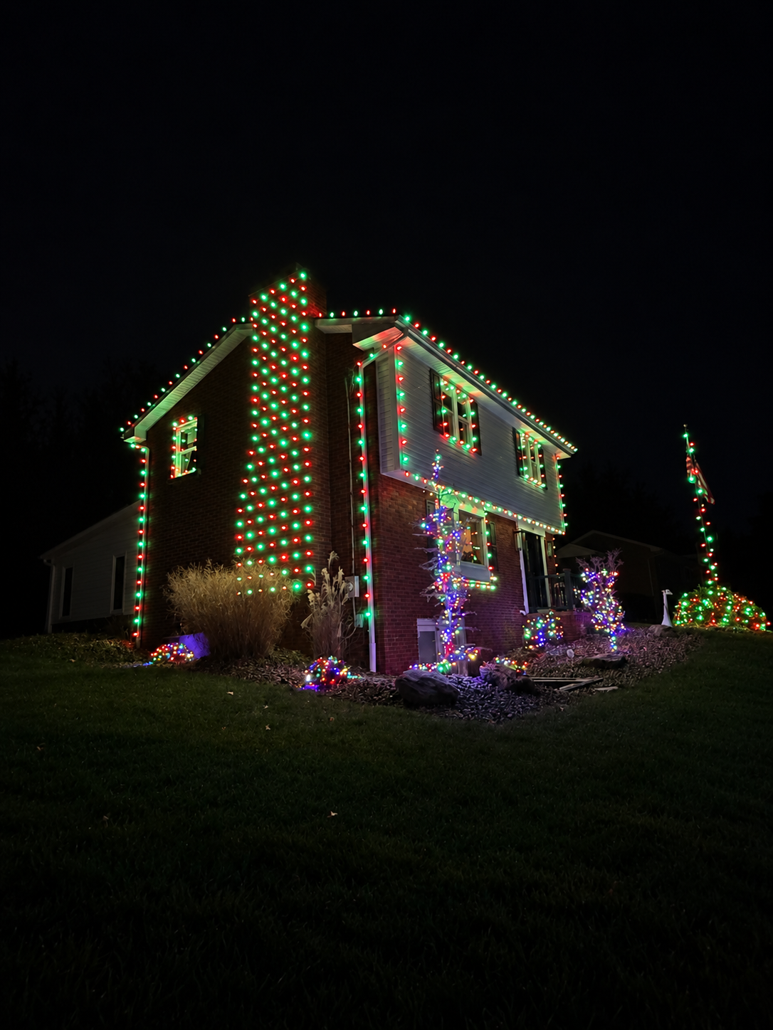 Red and green lights outlining a home's chimney, roof, and windows